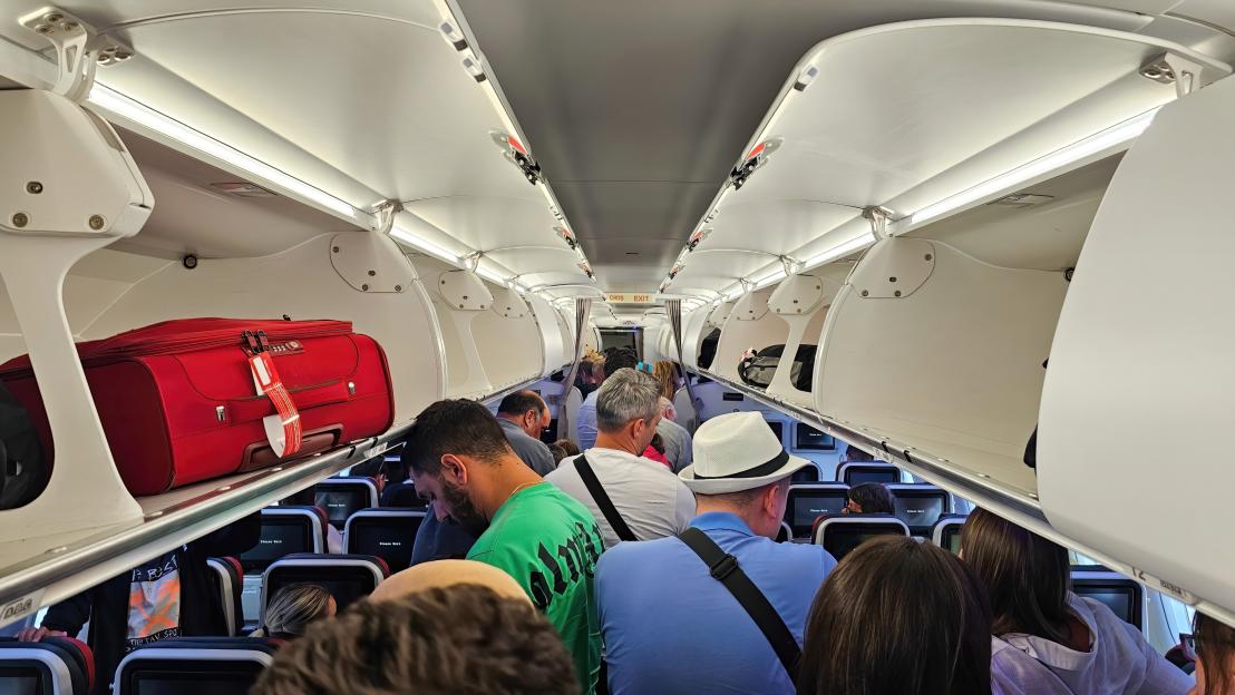 Passengers standing in an airplane aisle.