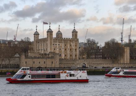 Tower of London with two City Cruises boats on the Thames River.