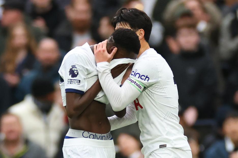 Pape Matar Sarr of Tottenham Hotspur being consoled by Son Heung-min after an injury.