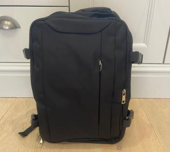 Black backpack on light wood floor.