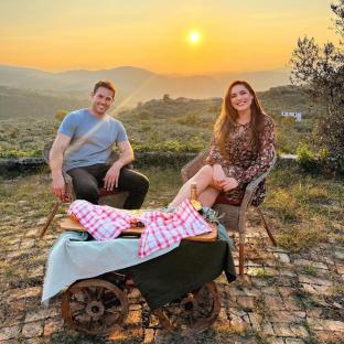 Kelly Brook and a man sitting outdoors at sunset, enjoying a meal.