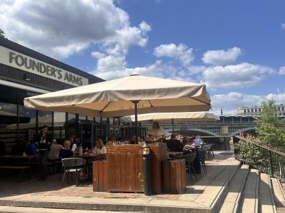 Patrons seated at outdoor tables under umbrellas at Founder's Arms.