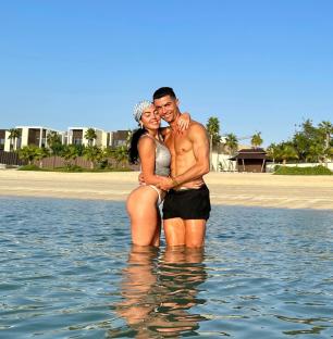 Georgina Rodriguez and Cristiano Ronaldo embracing in shallow water.