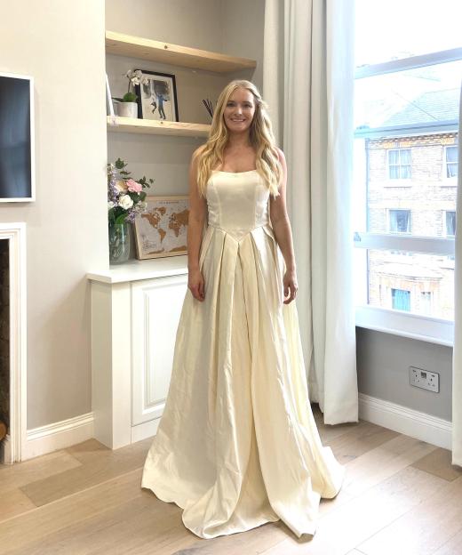 Woman in a cream-colored wedding dress in a living room.