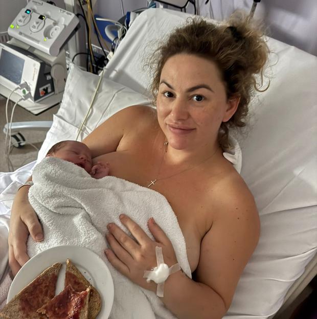 A mother holding her newborn baby in a hospital bed.