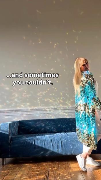 Woman in sequined robe in front of a couch.