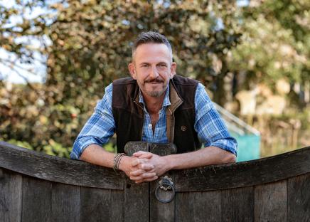 Man leaning on a wooden gate.