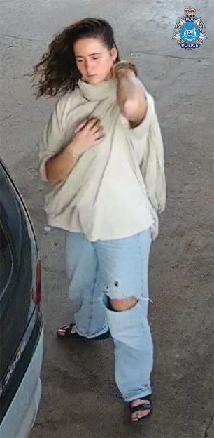Woman in light-colored sweater and jeans near a car.