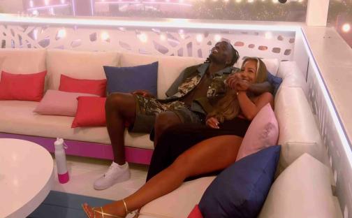 Meg and Dejon cuddling on a couch.
