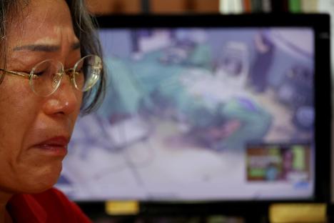 A woman points at a computer screen showing a surgery; another woman sits beside her.