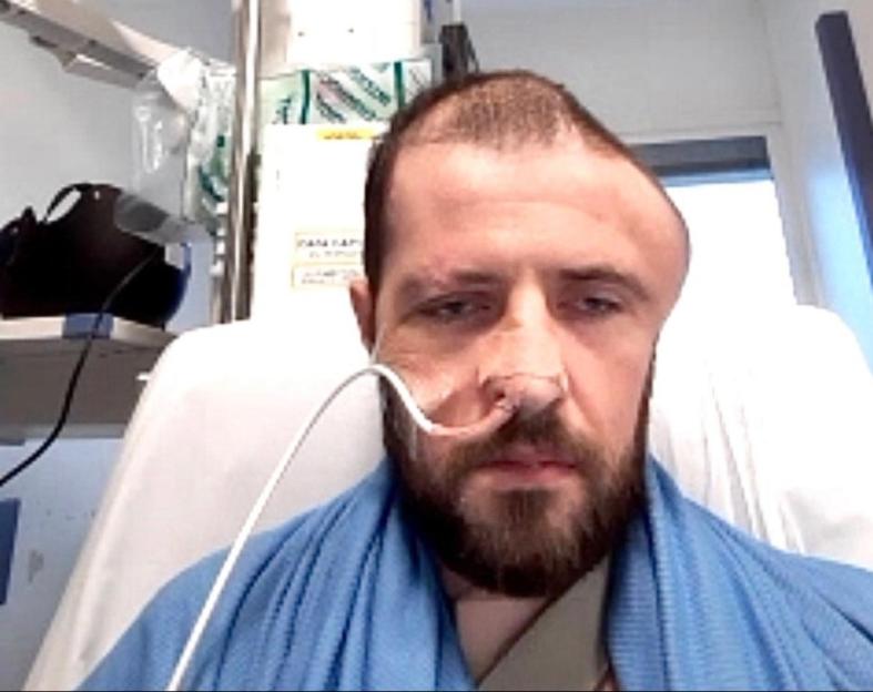 Man in hospital bed with head injury.