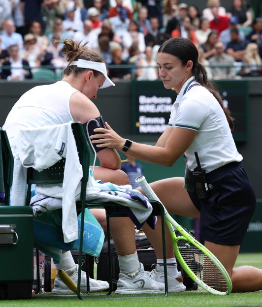 A tennis player receives medical attention during a match.