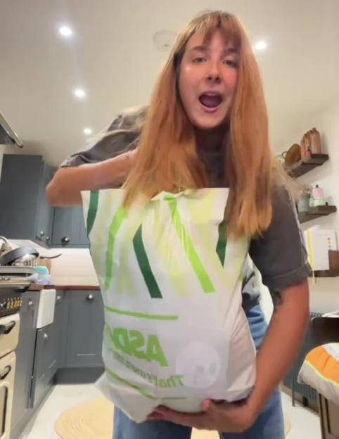 Woman holding a large grocery bag of produce.
