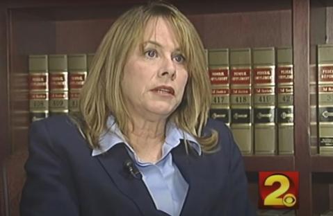 Woman in a navy blazer sits for an interview.