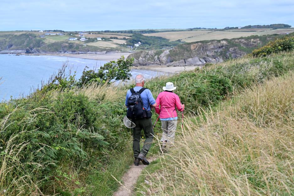 Elderly couple hiking on coastal path.