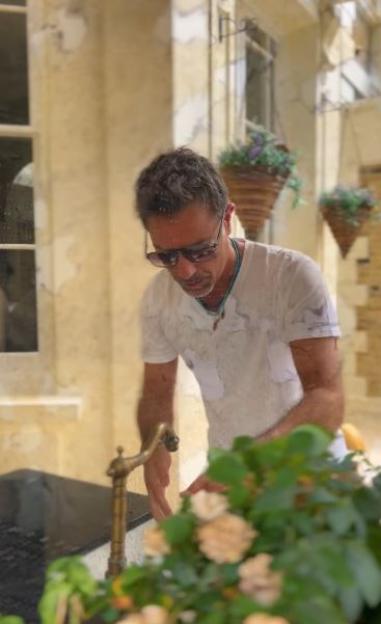 Gino D’Acampo washing his hands at an outdoor sink.