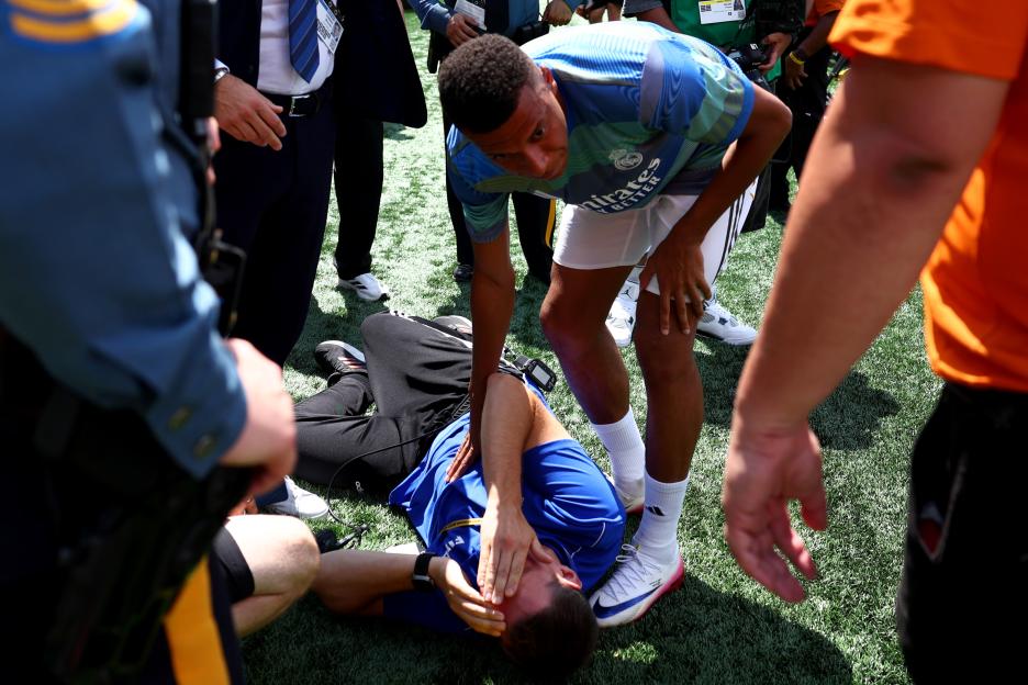 Kylian Mbappé checking on a volunteer injured by a ball during a soccer game.