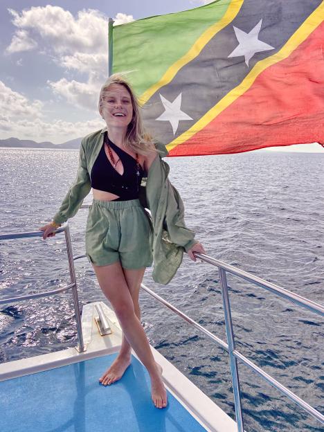 Woman standing on a boat with a St. Kitts and Nevis flag in the background.