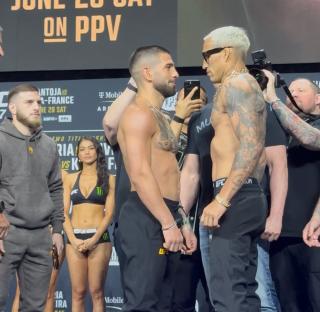 Two shirtless MMA fighters facing each other at a weigh-in.
