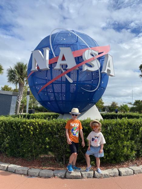 Two children stand in front of a large NASA globe.