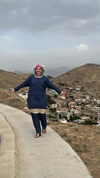 Woman walking on a path overlooking a town in Afghanistan.