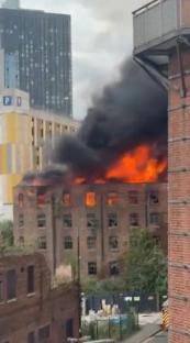 Large fire engulfing a brick building in Manchester.