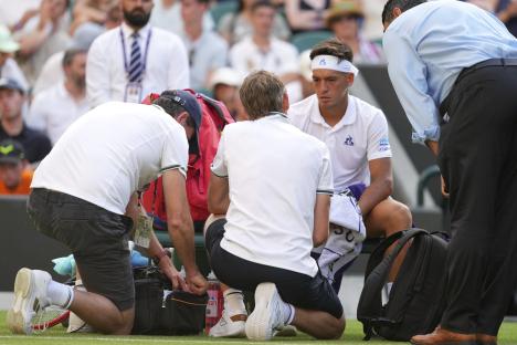 Sebastian Baez of Argentina receiving medical attention during a Wimbledon tennis match.