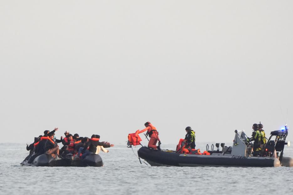 Migrants in an inflatable boat are given life jackets by French authorities.