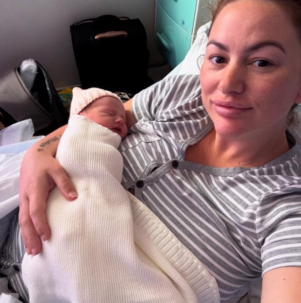 New mother holding her newborn baby in a hospital bed.