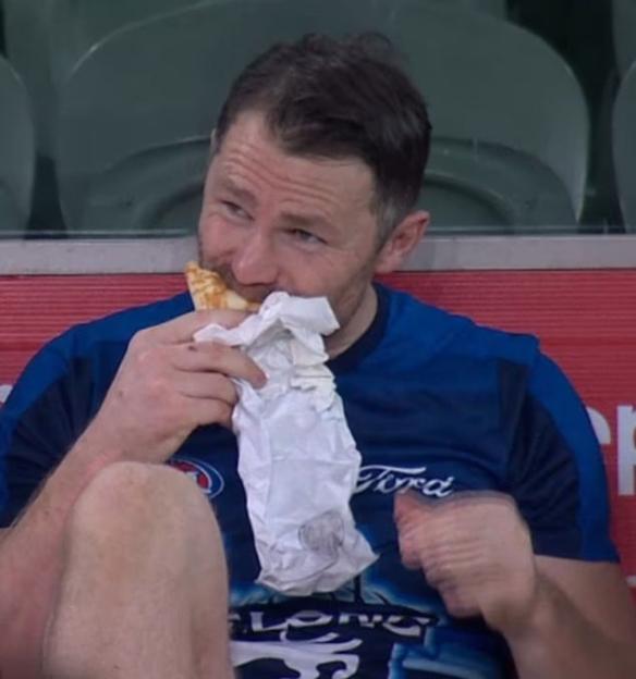 Sports star eating a kebab on a bench.