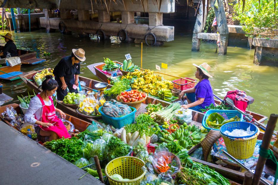 Women selling fruit and vegetables from boats at a floating market.