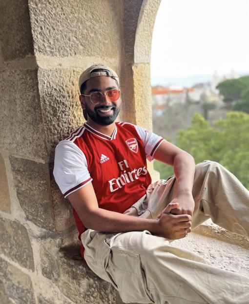 Man in Arsenal jersey sitting in a stone alcove.