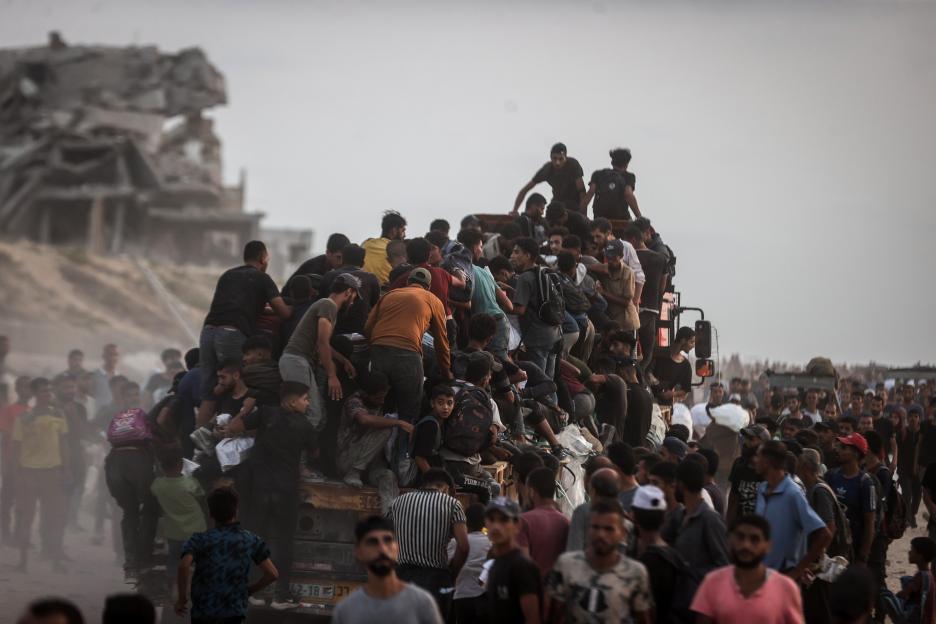Palestinians crowd onto a truck to receive food aid.