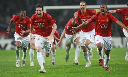 Manchester United players celebrating a victory on a rain-soaked field.