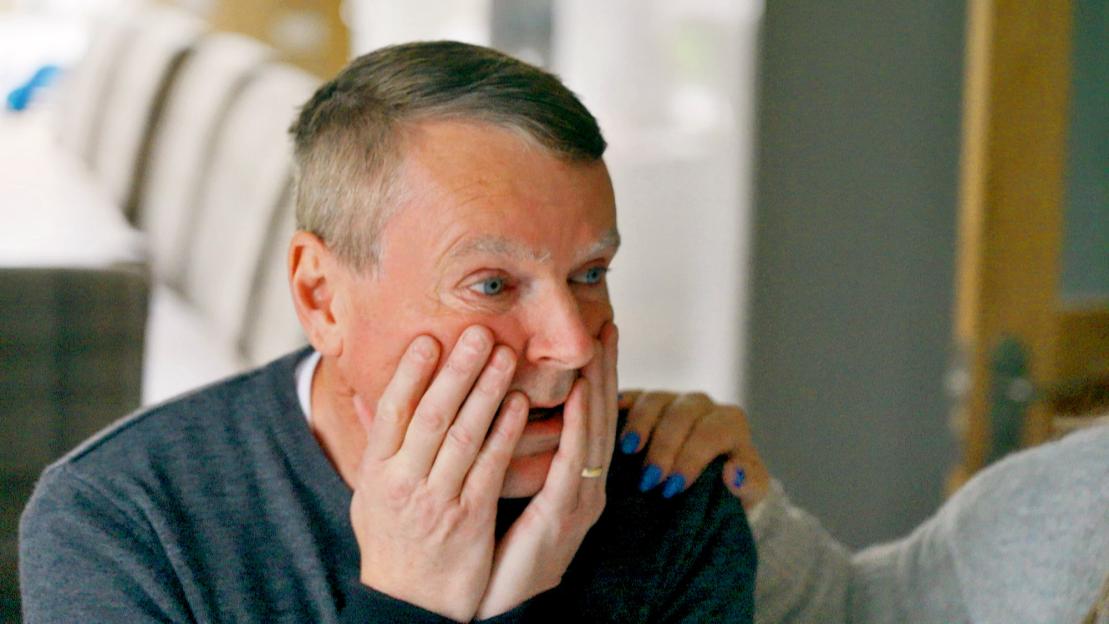 A man reacting emotionally, with a hand on his shoulder.