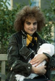 Linda Davidson as Mary Smith from EastEnders holding a baby.