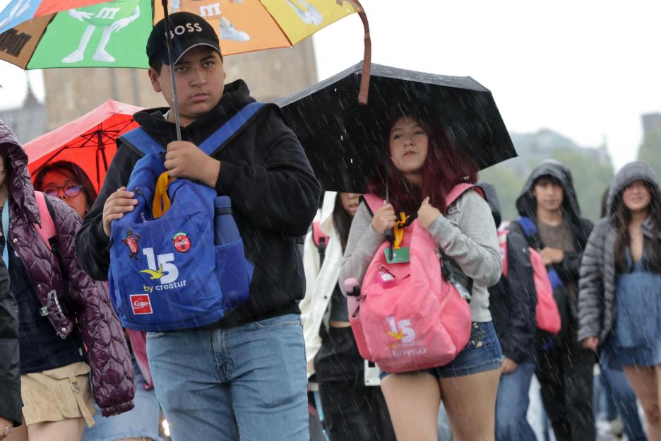 Tourists sheltering under umbrellas in the rain.