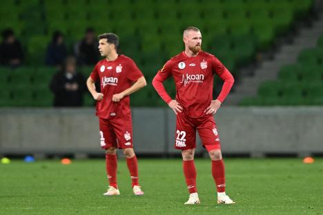 Two soccer players in red uniforms on a field.