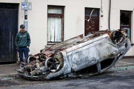 Burnt-out car on street after anti-immigration riot.