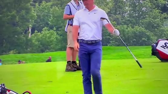 Rory McIlroy walking on a golf course after a shot.