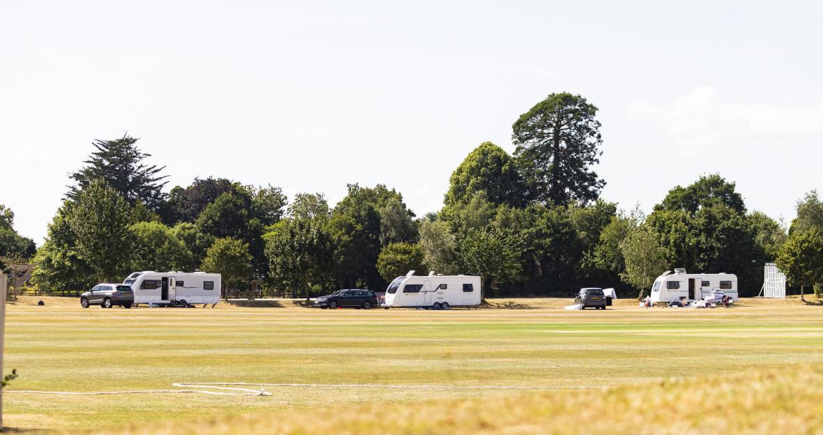 Caravans parked on a cricket pitch.