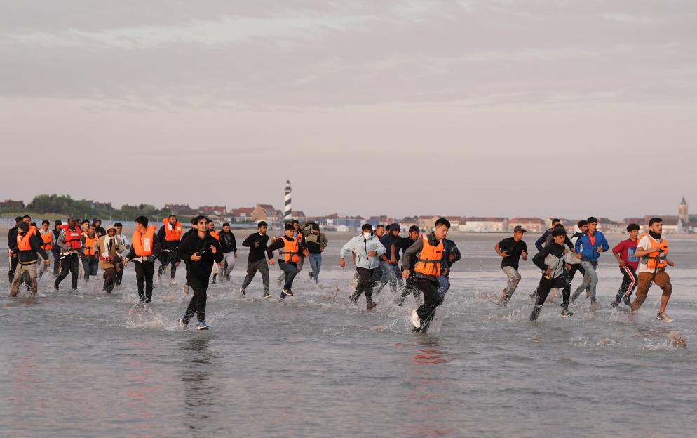 Migrants running into the water to board a small boat.