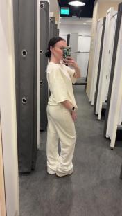 Woman in a cream-colored tracksuit in a Primark changing room.