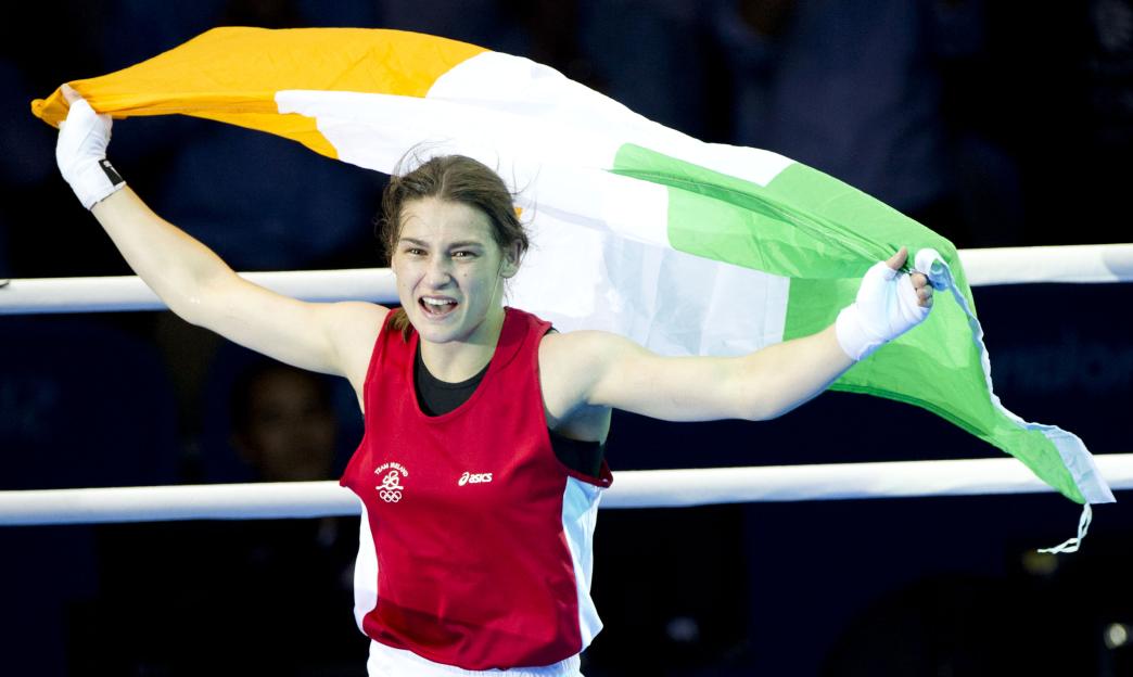 Katie Taylor, an Irish boxer, celebrates her gold medal win at the Olympics, holding the Irish flag.