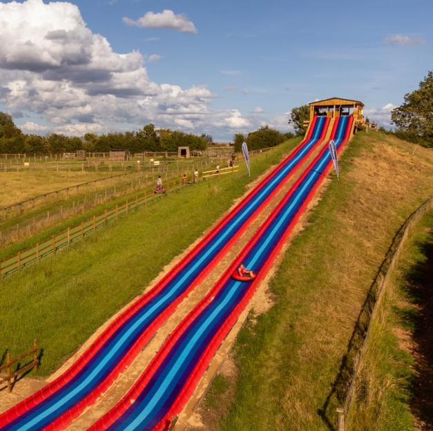 Person sliding down long, striped hill slide at National Forest Adventure Farm.