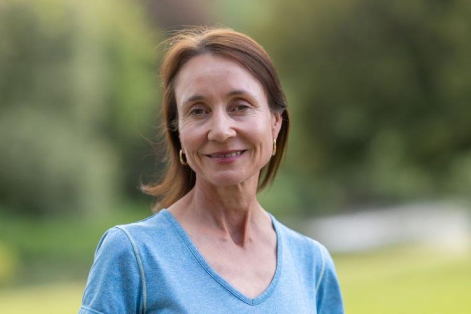 a woman in a blue shirt is smiling for the camera
