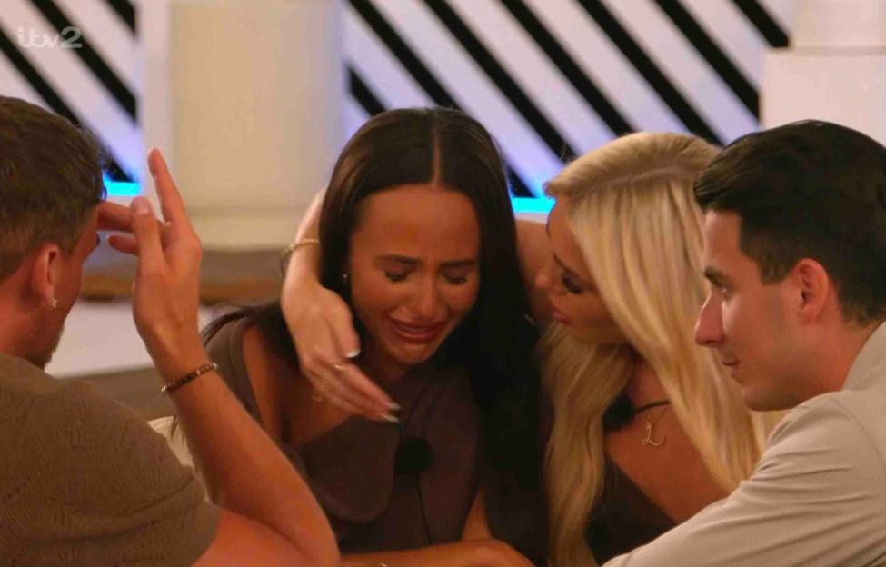 Screenshot from Love Island showing a woman crying while being comforted by two other women and a man.