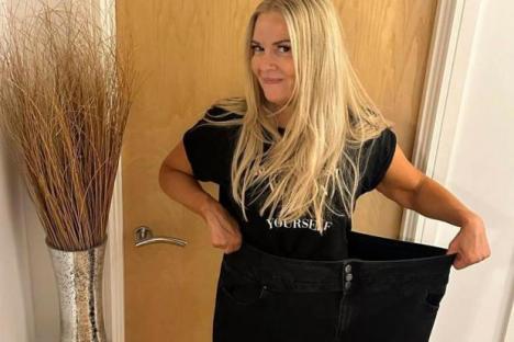 Woman holding up large jeans after weight loss.