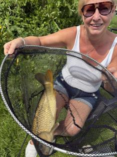 Woman holding a large fish in a net.
