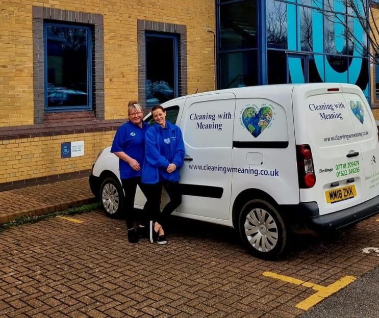 Two women standing by a Cleaning with Meaning van.